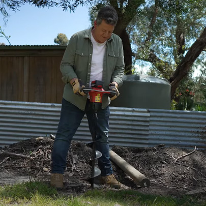 A man drills a hole with an auger